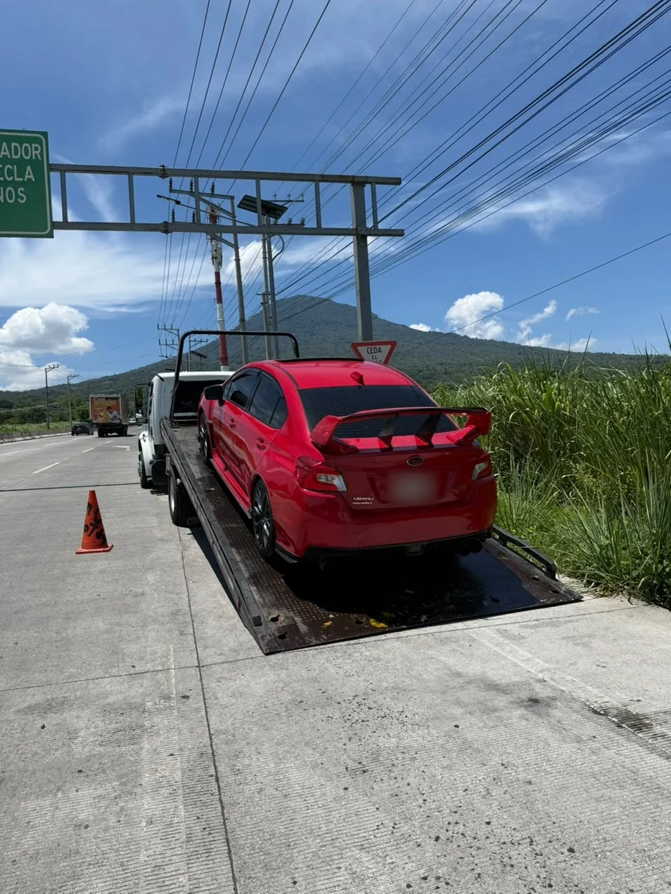 Carga de un auto deportivo rojo en carretera