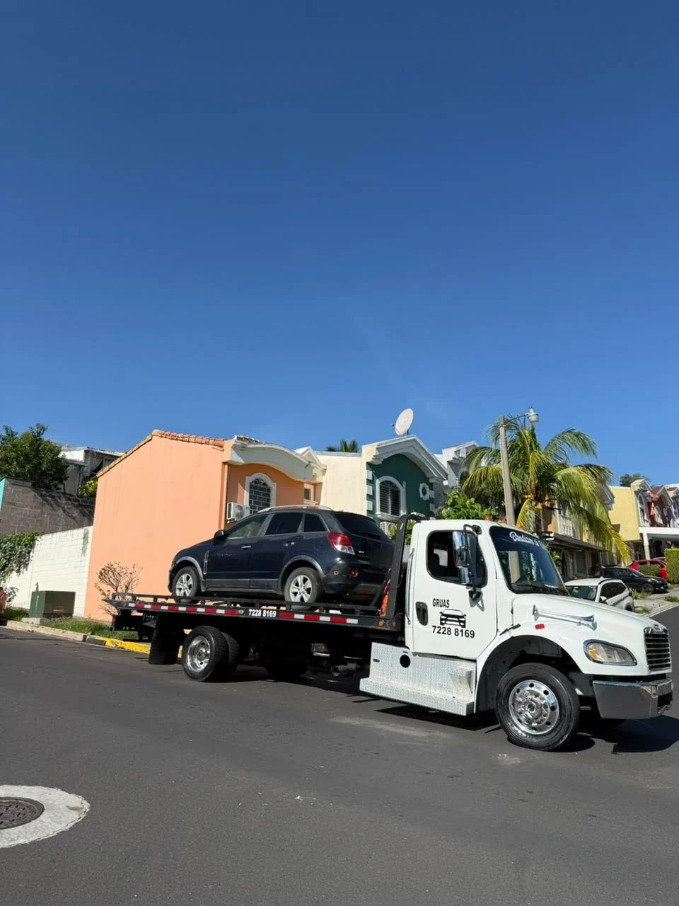 Grúa en zona residencial con una camioneta negra