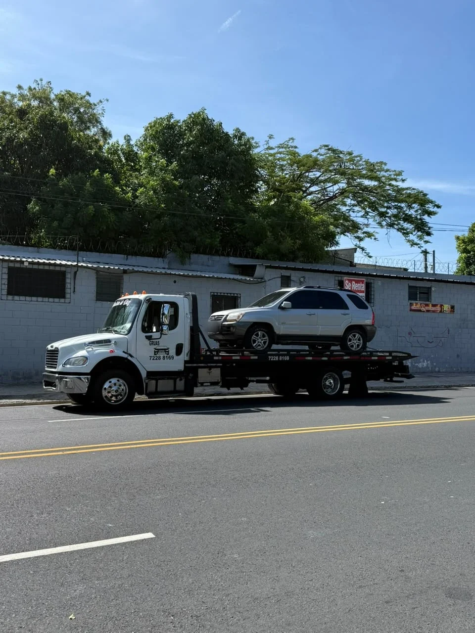 Grúa trasladando una camioneta plateada
